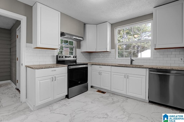 kitchen featuring white cabinetry, sink, stainless steel appliances, wall chimney range hood, and tasteful backsplash