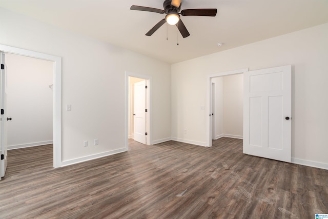 unfurnished bedroom with a closet, a walk in closet, dark hardwood / wood-style floors, and ceiling fan