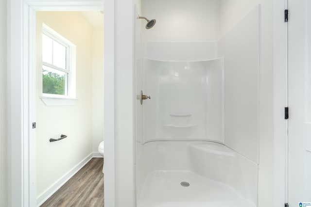 bathroom featuring a shower, hardwood / wood-style flooring, and toilet