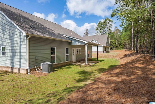 rear view of property with a lawn, a patio, and central AC