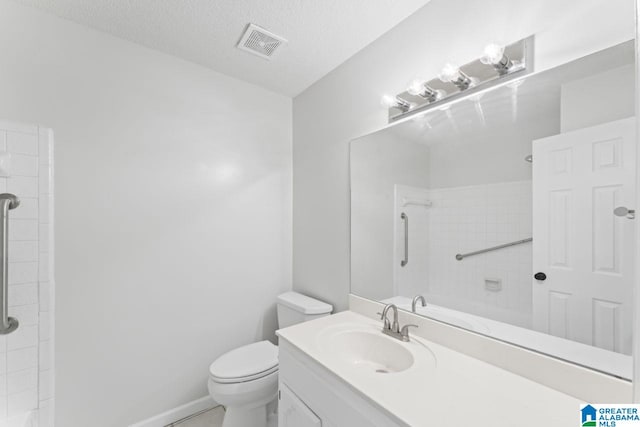 bathroom featuring vanity, a textured ceiling, tiled shower, and toilet