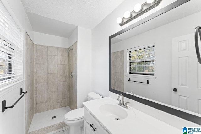 bathroom with toilet, a textured ceiling, tile patterned floors, and a healthy amount of sunlight