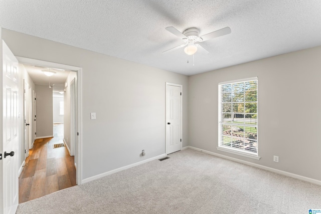 unfurnished room featuring ceiling fan, light wood-type flooring, and a textured ceiling