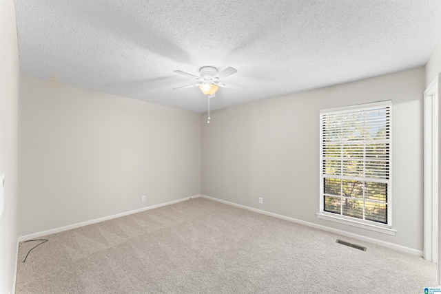 carpeted spare room featuring ceiling fan and a textured ceiling