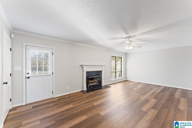 unfurnished living room featuring a textured ceiling, a fireplace, dark wood-type flooring, and a wealth of natural light