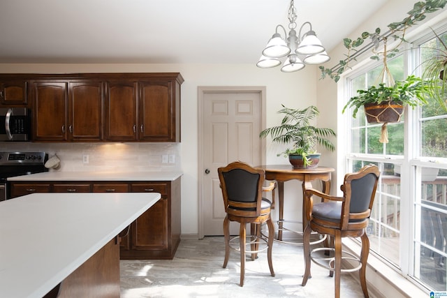 kitchen featuring decorative backsplash, dark brown cabinets, stainless steel appliances, and a wealth of natural light