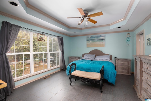 bedroom featuring a raised ceiling, multiple windows, ornamental molding, and ceiling fan