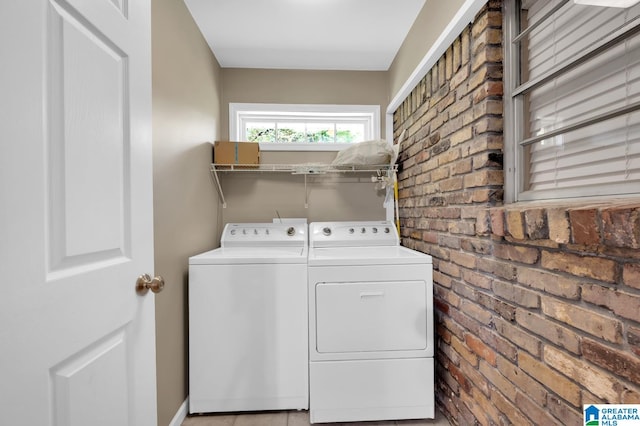 washroom featuring washer and dryer and brick wall