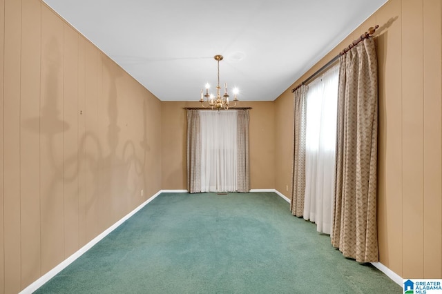 spare room with carpet flooring, a notable chandelier, and wood walls