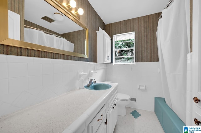 bathroom featuring tile patterned flooring, vanity, toilet, and tile walls