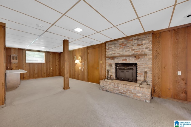 basement with wooden walls, a drop ceiling, and light colored carpet