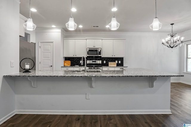 kitchen featuring dark hardwood / wood-style floors, white cabinets, stainless steel appliances, and decorative light fixtures