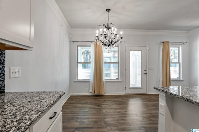 unfurnished dining area with a wealth of natural light, crown molding, dark wood-type flooring, and a notable chandelier