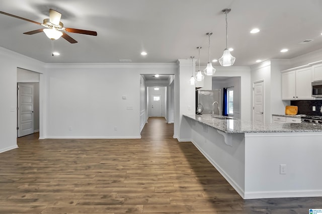 kitchen featuring dark wood-type flooring, sink, decorative light fixtures, white cabinetry, and stainless steel appliances