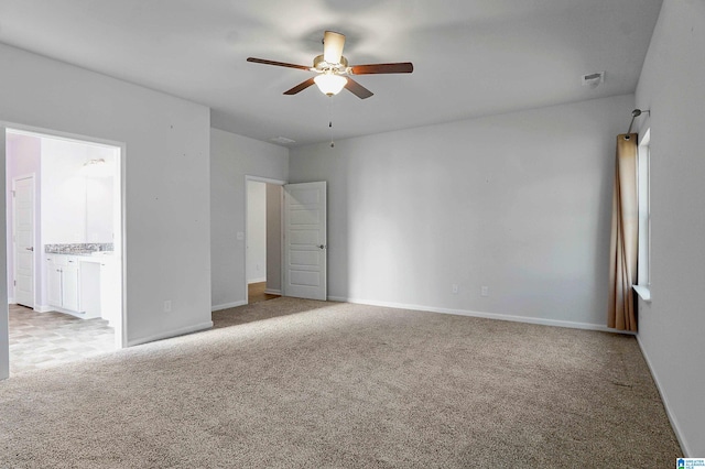 unfurnished bedroom with ceiling fan, light colored carpet, and ensuite bath