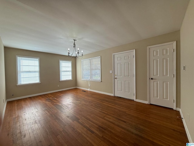 unfurnished room featuring dark hardwood / wood-style flooring and a notable chandelier