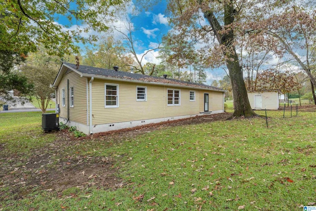 rear view of house featuring a shed, central AC unit, and a lawn