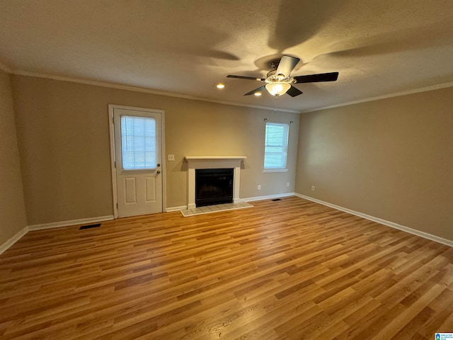 unfurnished living room with ceiling fan, a fireplace, light hardwood / wood-style floors, and ornamental molding