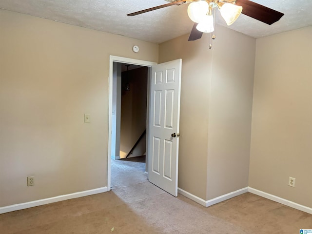 carpeted spare room featuring a textured ceiling and ceiling fan