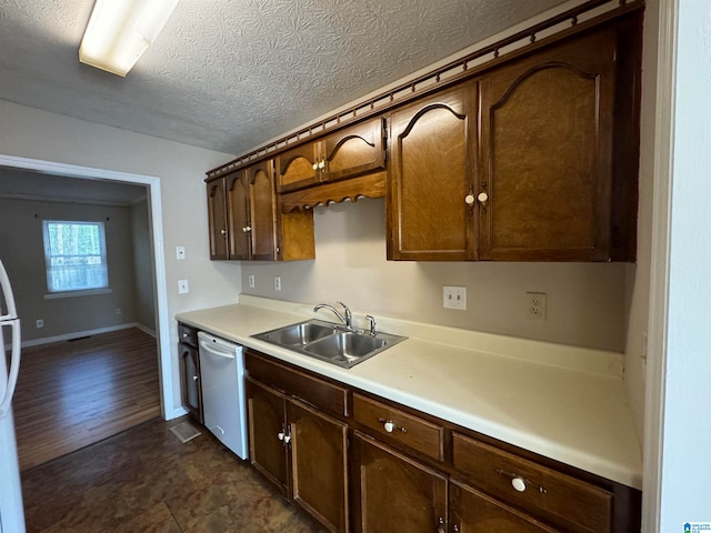 kitchen with stainless steel dishwasher, a textured ceiling, dark brown cabinetry, dark wood-type flooring, and sink