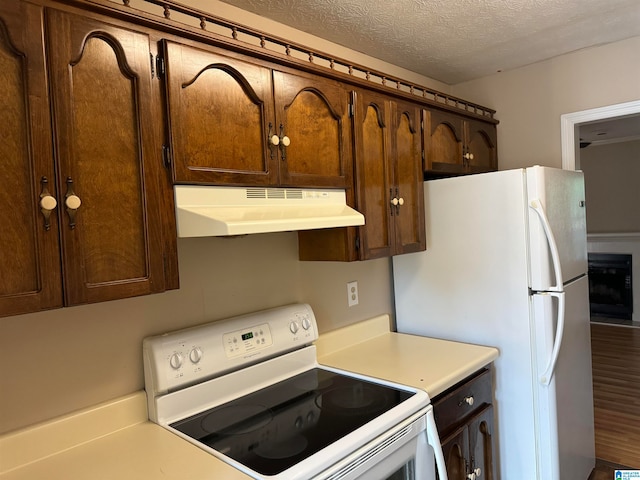 kitchen featuring hardwood / wood-style floors, white appliances, and a textured ceiling