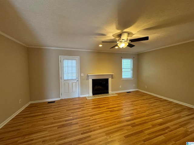 unfurnished living room featuring a healthy amount of sunlight, a fireplace, light hardwood / wood-style floors, and a textured ceiling