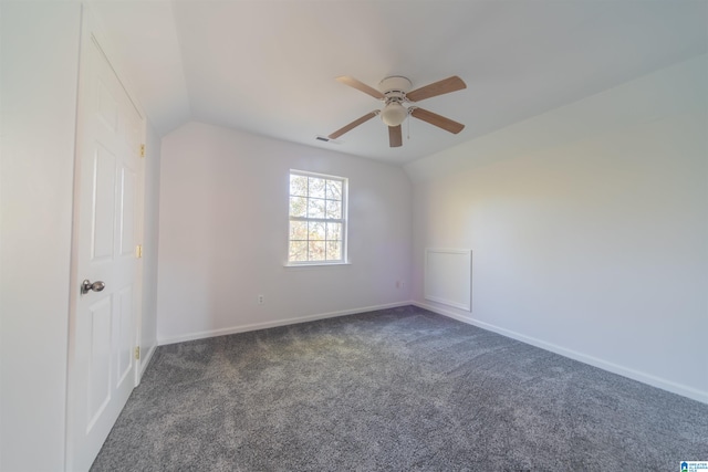 unfurnished room featuring ceiling fan, vaulted ceiling, and dark colored carpet