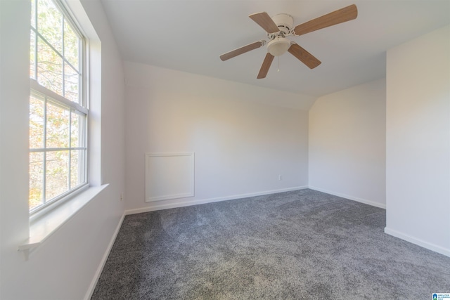 unfurnished room featuring dark colored carpet, plenty of natural light, and ceiling fan