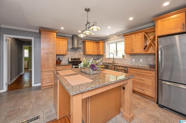 kitchen with light stone countertops, wall chimney exhaust hood, stainless steel appliances, sink, and a center island