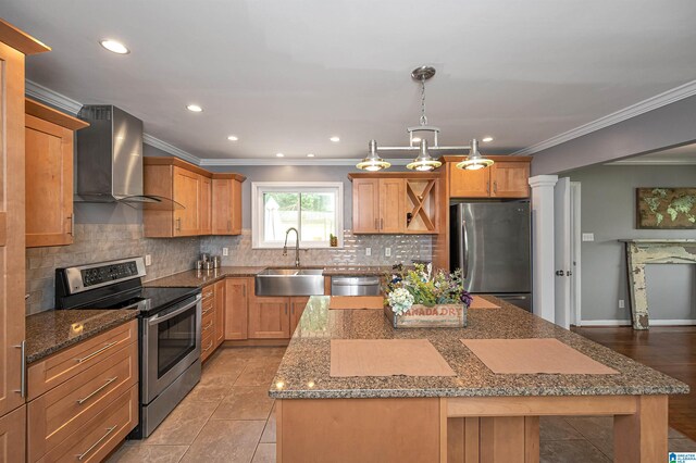 kitchen with appliances with stainless steel finishes, crown molding, sink, wall chimney range hood, and a center island