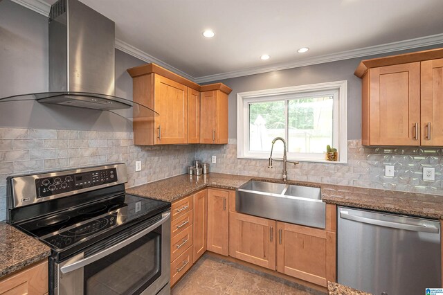 kitchen with sink, wall chimney range hood, dark stone counters, appliances with stainless steel finishes, and ornamental molding