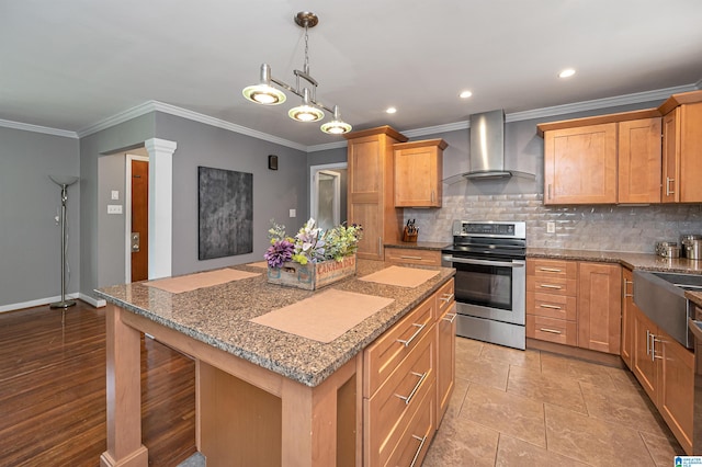 kitchen featuring a center island, hanging light fixtures, wall chimney exhaust hood, ornamental molding, and stainless steel range