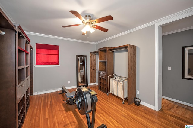 workout area featuring ceiling fan, wood-type flooring, a baseboard heating unit, and ornamental molding