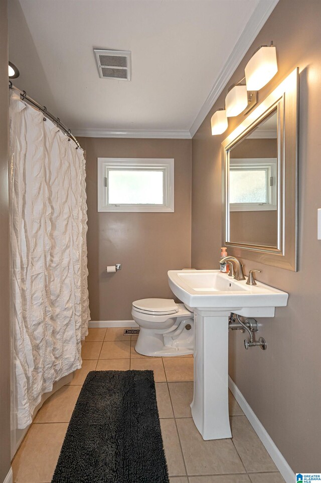 bathroom featuring a wealth of natural light, tile patterned flooring, crown molding, and toilet