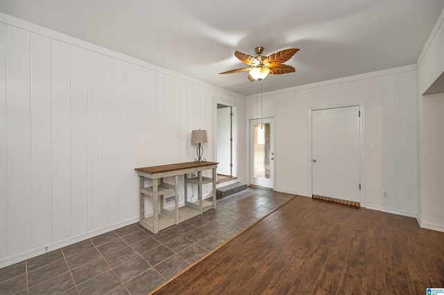 entrance foyer featuring wood walls, dark hardwood / wood-style floors, ceiling fan, and ornamental molding