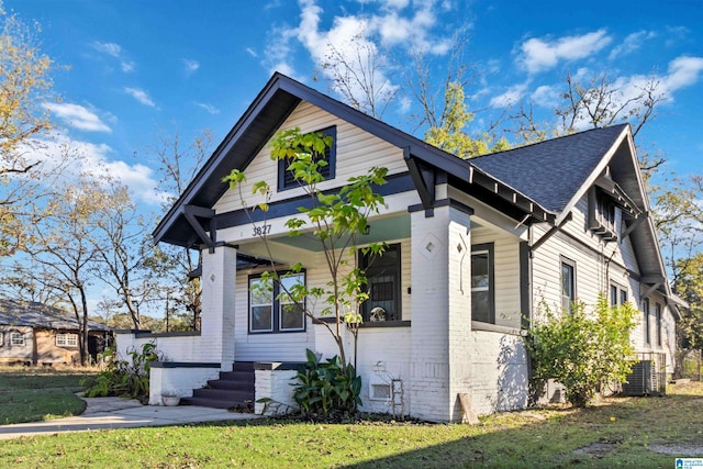 view of front of property with covered porch, central AC, and a front lawn