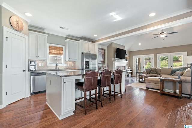 kitchen featuring a kitchen bar, dark wood-type flooring, a center island, and stainless steel appliances