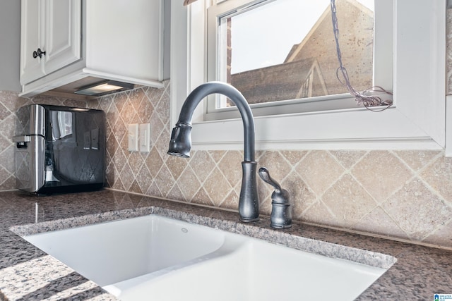 room details featuring decorative backsplash, white cabinets, and sink