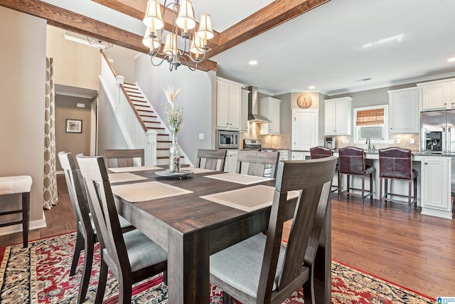 dining space with beam ceiling, ornamental molding, dark wood-type flooring, and an inviting chandelier