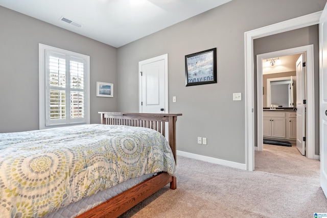 bedroom with ensuite bathroom and light colored carpet