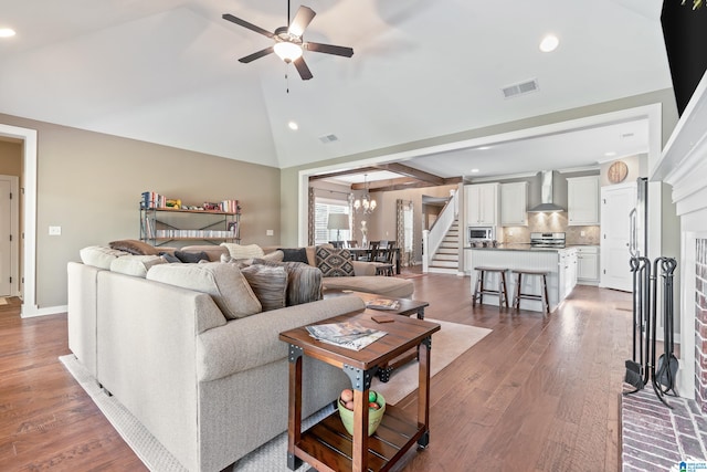 living room featuring ceiling fan with notable chandelier, wood-type flooring, and vaulted ceiling