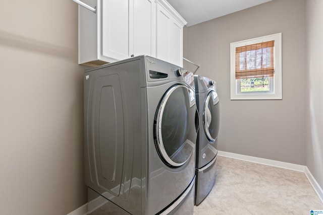 clothes washing area featuring cabinets and washing machine and clothes dryer