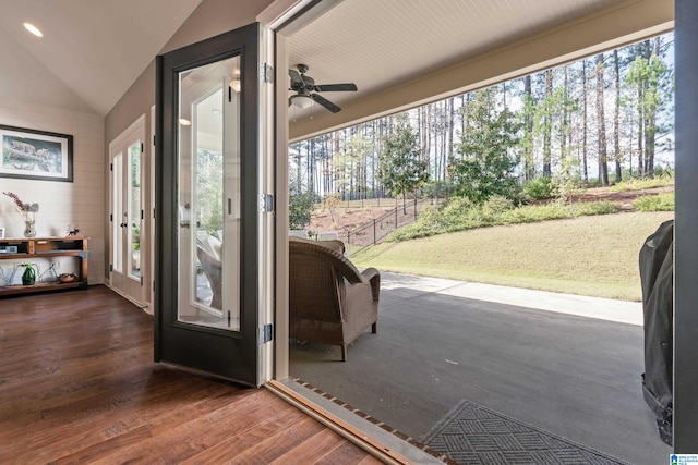 doorway with dark hardwood / wood-style floors, vaulted ceiling, and ceiling fan