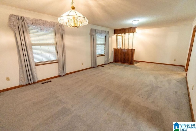 carpeted spare room featuring a chandelier, a textured ceiling, and ornamental molding