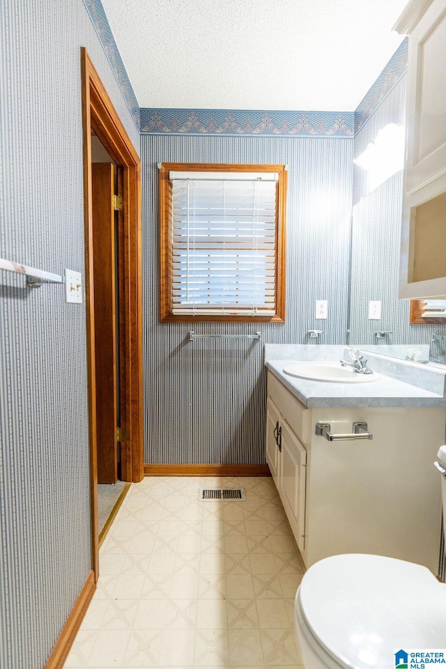 bathroom featuring a textured ceiling, vanity, and toilet