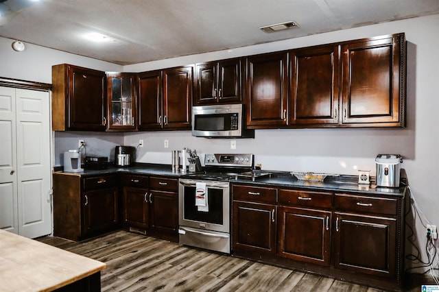 kitchen featuring hardwood / wood-style floors, dark brown cabinetry, and appliances with stainless steel finishes