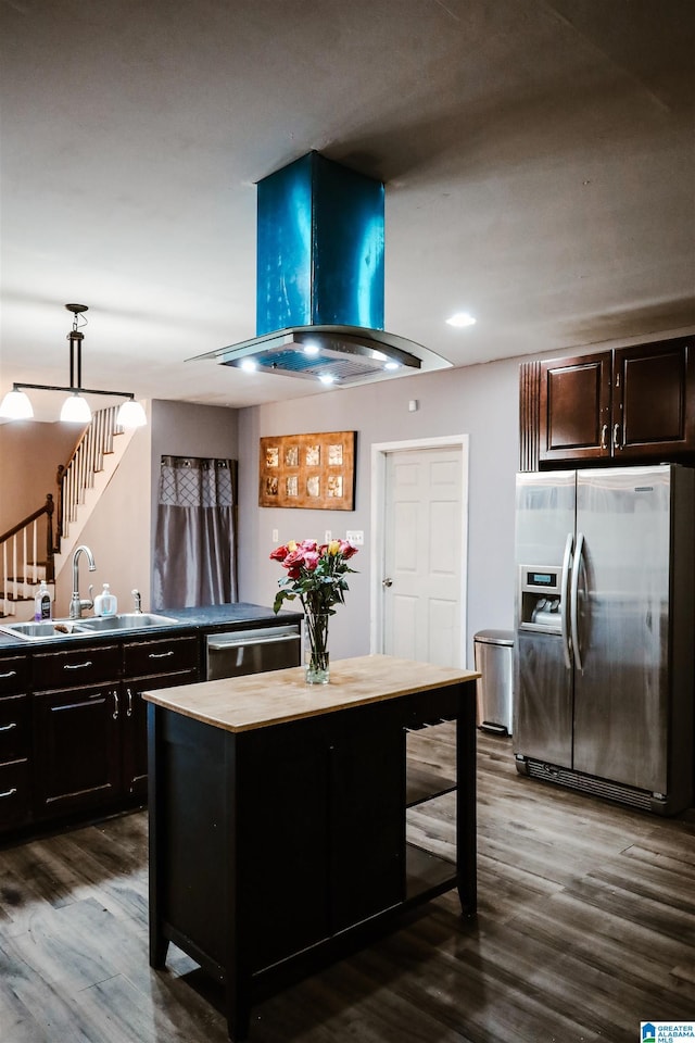 kitchen featuring appliances with stainless steel finishes, dark wood-type flooring, wall chimney range hood, sink, and a kitchen island