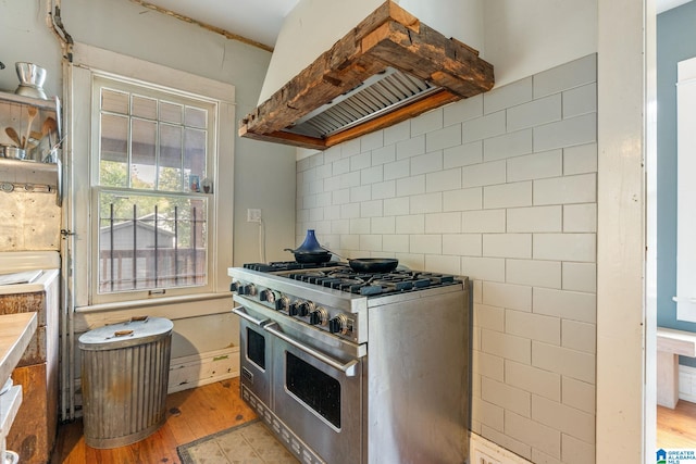 kitchen with premium range hood, high end stainless steel range, light hardwood / wood-style floors, and tile walls