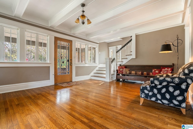 foyer entrance featuring hardwood / wood-style floors, beamed ceiling, an inviting chandelier, and ornamental molding