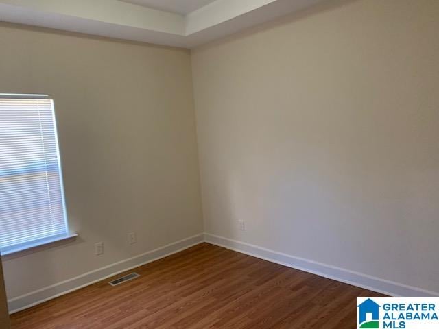 empty room with dark hardwood / wood-style flooring and a wealth of natural light